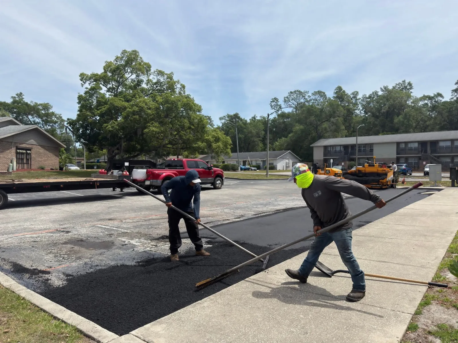 Workers applying sealcoat to an asphalt surface in a residential community