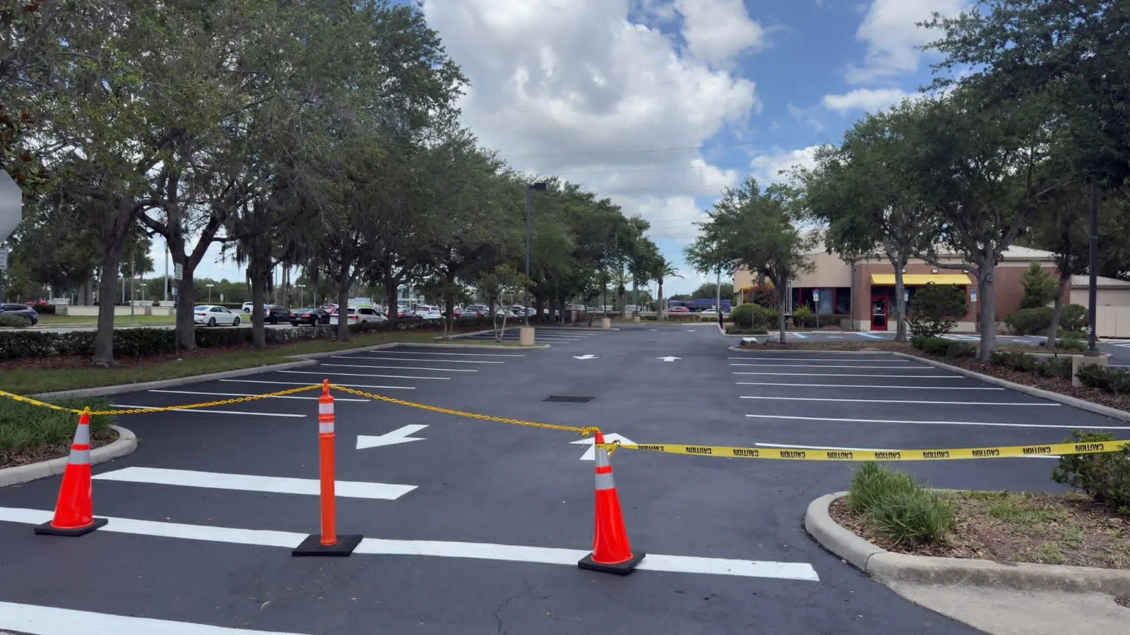 Freshly resurfaced commercial parking lot closed off with cones and caution tape
