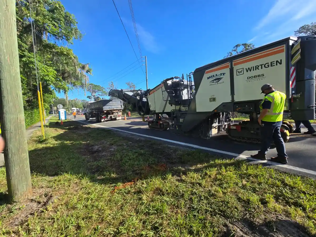 Wirtgen milling machine working a Daytona Beach road lane while a dump truck takes the millings off its conveyor