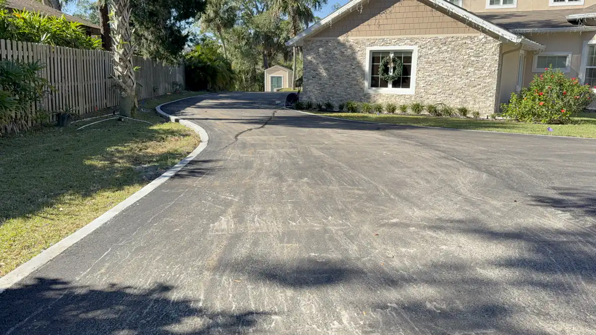Finished asphalt cul-de-sac in DeLand, Florida, running past a stone-faced home to a clean concrete curb