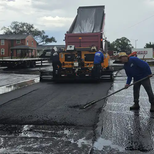 M&S Asphalt Paving crew member luting the seam between new and existing asphalt on a wet apartment complex lot in DeBary, Florida