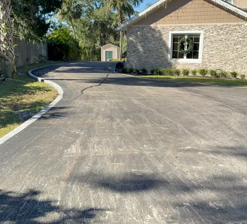 Finished asphalt driveway curving past a stone-faced home in DeLand, Florida