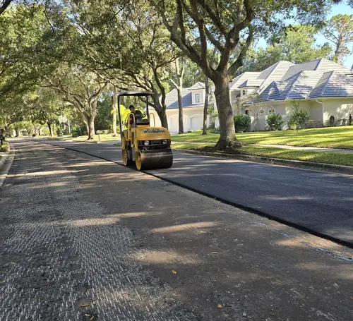 Roller compacting a newly paved residential street lined with oaks in DeLand, Florida