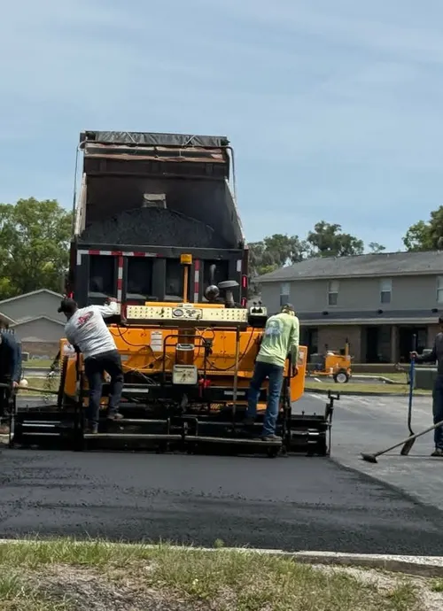 M&S Asphalt Paving crew feeding a paver from a dump truck over a freshly built road base