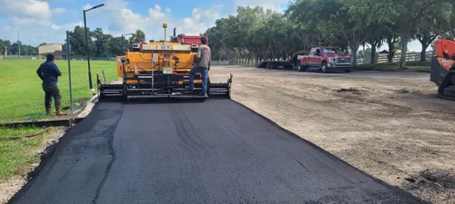 M&S Asphalt Paving machine laying a new asphalt surface along a tree lined road in Volusia County