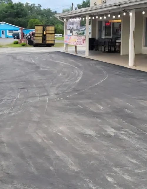 Commercial lot beside an open storefront, paved in sections so the business could keep trading