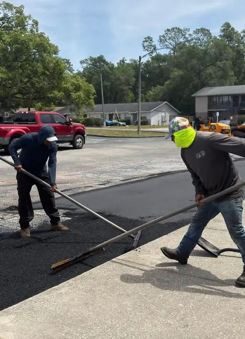 M&S Asphalt Paving crew raking fresh asphalt across a prepared base in DeLand, Florida