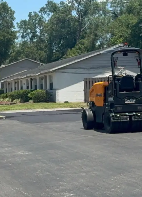 Roller finishing a new asphalt driveway beside a DeLand, Florida home