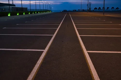 Newly striped commercial asphalt parking lot photographed at dusk