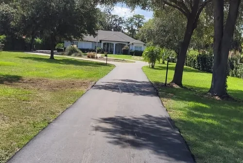 Freshly paved residential driveway curving up to a Florida home surrounded by oak trees