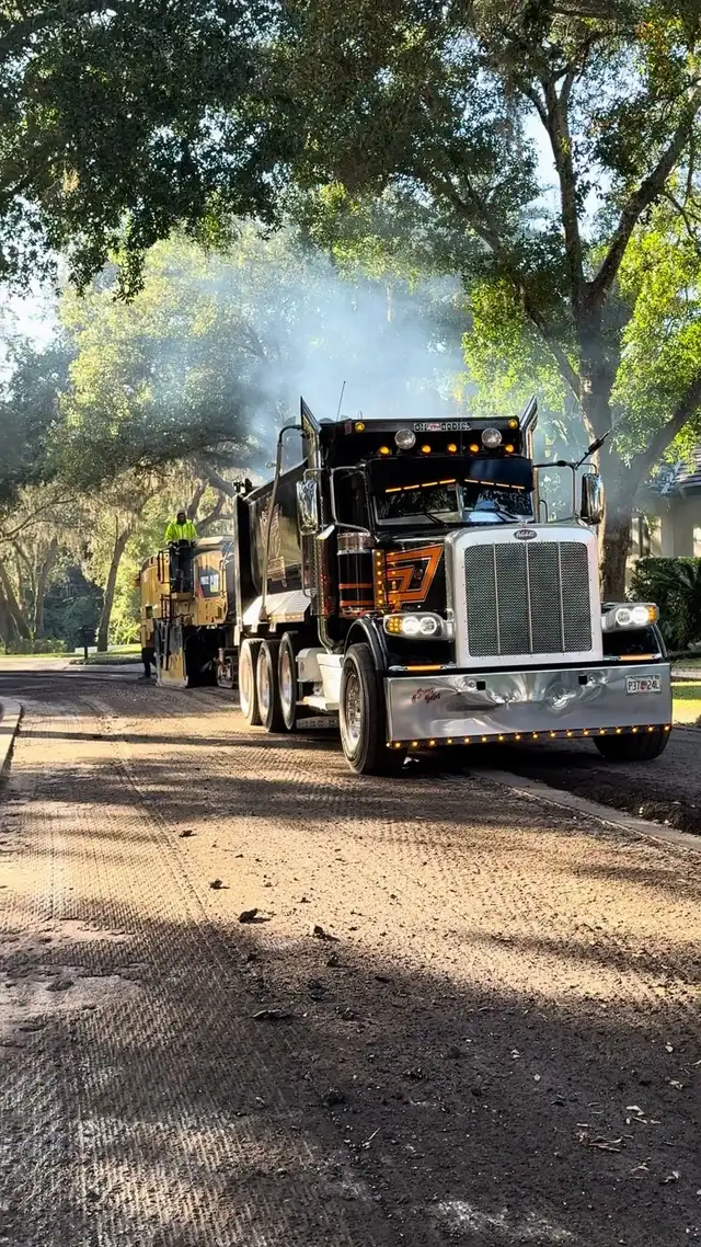 Loaded dump truck pulling away from the milling machine on a residential street in DeLand, Florida