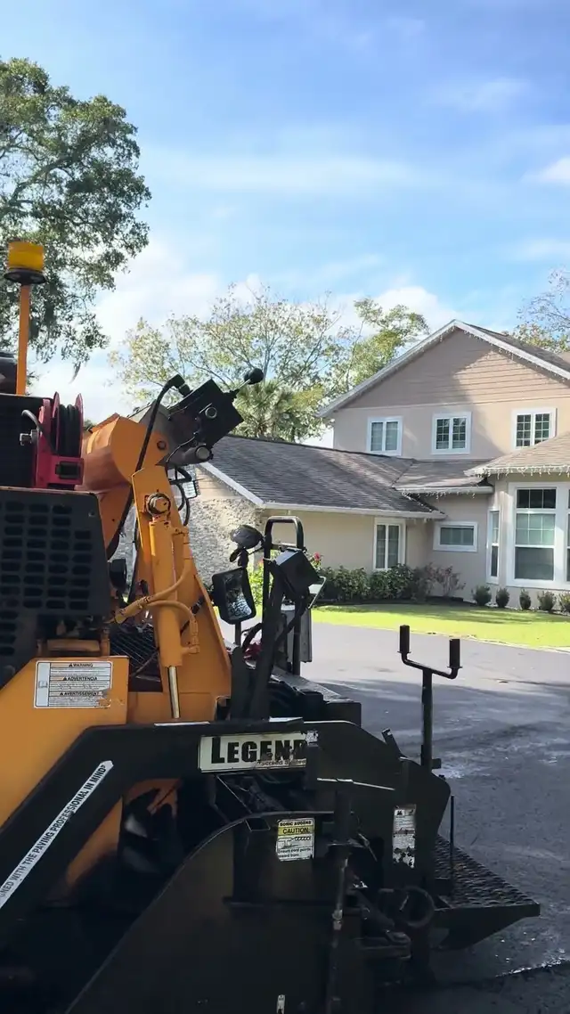 LeeBoy paver screed on the freshly laid cul-de-sac in DeLand, Florida, with the finished home behind it